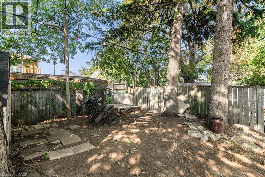 Private outdoor space with mature trees, a wooden privacy fence, and concrete stepping stones - 29 Wexford Avenue N, Hamilton, ON