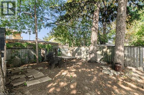 Private outdoor space with mature trees, a wooden privacy fence, and concrete stepping stones - 29 Wexford Avenue N, Hamilton, ON 