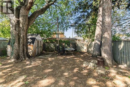 Expansive backyard featuring mature trees, a wooden storage shed, and a privacy fence - 29 Wexford Avenue N, Hamilton, ON 