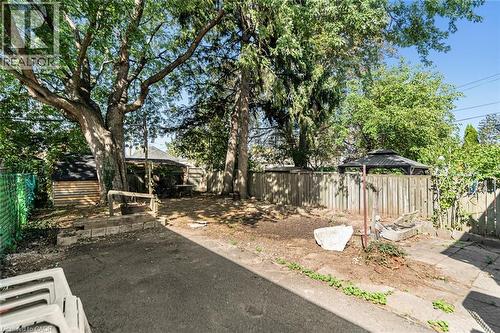 Spacious backyard featuring mature trees, wood fencing, and a built-in shed structure - 29 Wexford Avenue N, Hamilton, ON 
