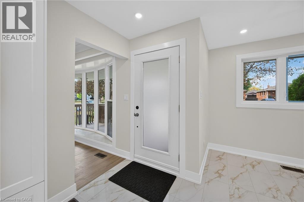 Entryway featuring a solid core door with frosted glass panel, recessed lighting, and white baseboards - 331 East 17Th Street, Hamilton, ON