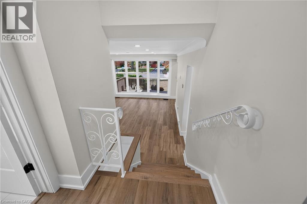Wood-finish flooring, white wrought iron railing, white trim, recessed lighting, and large windows - 331 East 17Th Street, Hamilton, ON