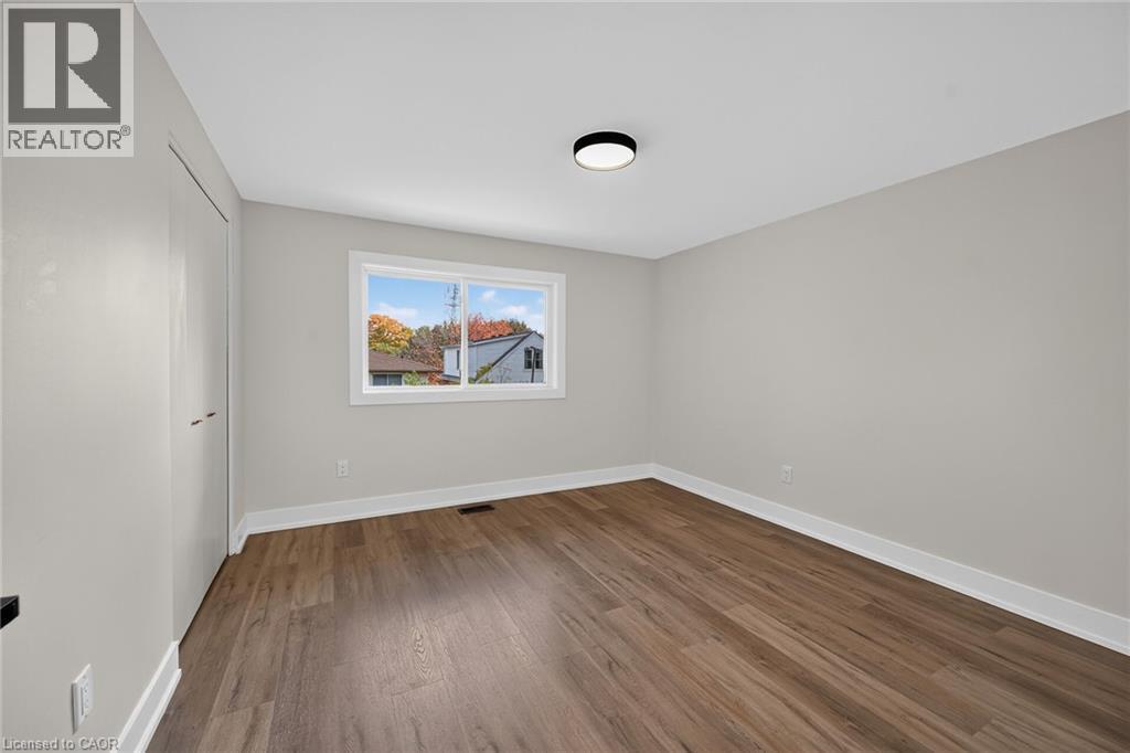 Wood-finish flooring, white trim, neutral wall color, contemporary ceiling light fixture, and window with white frame - 331 East 17Th Street, Hamilton, ON