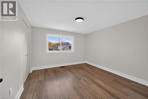 Wood-finish flooring, white trim, neutral wall color, contemporary ceiling light fixture, and window with white frame - 331 East 17Th Street, Hamilton, ON 