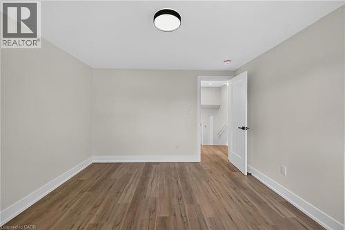 Recessed overhead lighting, wood-finish flooring, light-toned wall paint, white trim, and a white interior door with dark hardware - 331 East 17Th Street, Hamilton, ON 