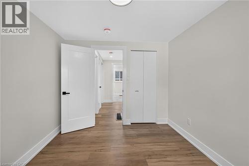 Wood-finish flooring, white bi-fold closet doors, white interior door with black hardware, recessed lighting, and light-toned wall finishes - 331 East 17Th Street, Hamilton, ON 