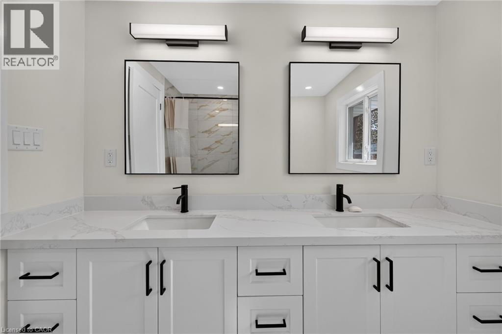 Dual vanity with white shaker-style cabinetry, quartz countertops, undermount sinks, matte black faucets, and rectangular mirrors with black frames - 331 East 17Th Street, Hamilton, ON