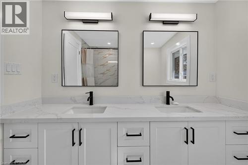Dual vanity with white shaker-style cabinetry, quartz countertops, undermount sinks, matte black faucets, and rectangular mirrors with black frames - 331 East 17Th Street, Hamilton, ON 