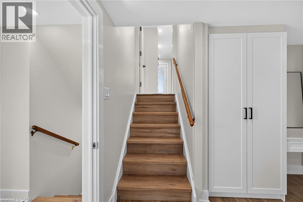 Wood-finish stairs with coordinating handrails, recessed ceiling lighting, and built-in white cabinetry with black hardware - 331 East 17Th Street, Hamilton, ON