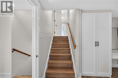 Wood-finish stairs with coordinating handrails, recessed ceiling lighting, and built-in white cabinetry with black hardware - 331 East 17Th Street, Hamilton, ON 