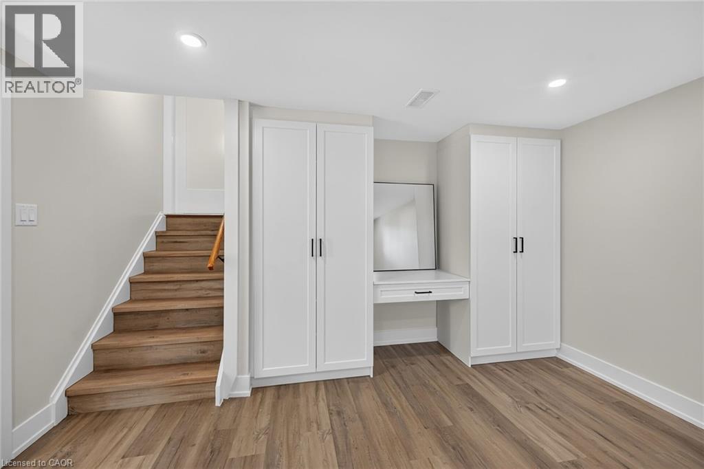 Wood-finish flooring, recessed lighting, and a built-in vanity with white cabinetry - 331 East 17Th Street, Hamilton, ON