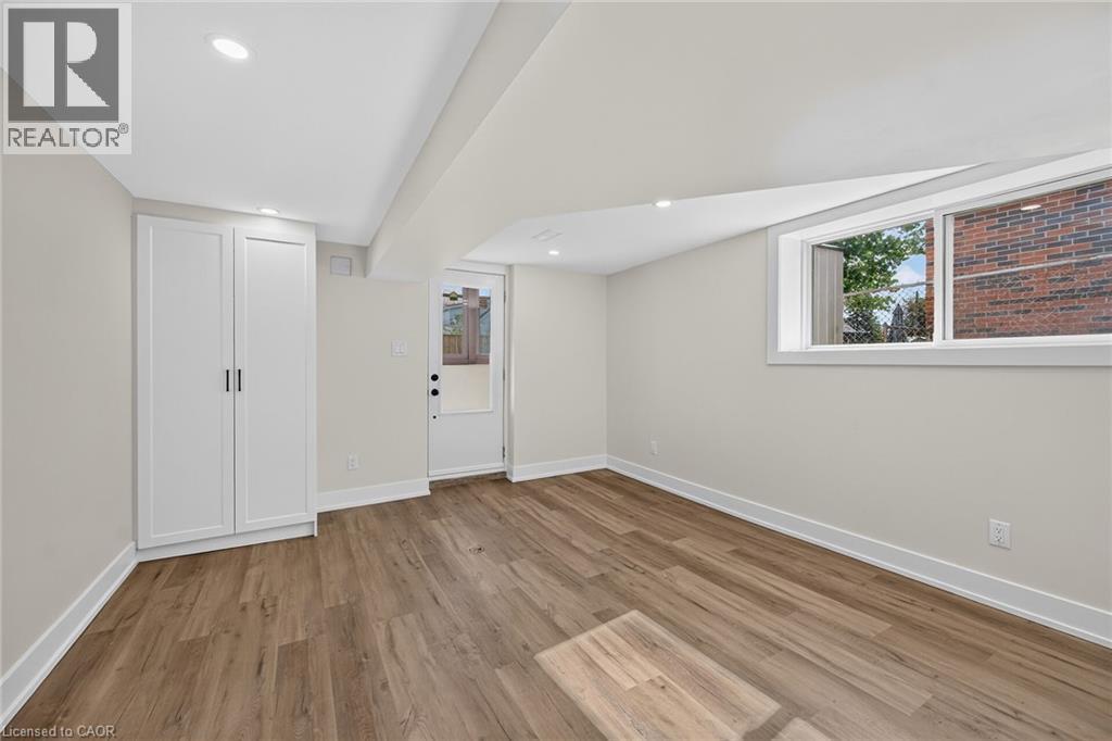 Wood-finish flooring, recessed lighting, white built-in cabinetry, modern white trim, and an egress window - 331 East 17Th Street, Hamilton, ON