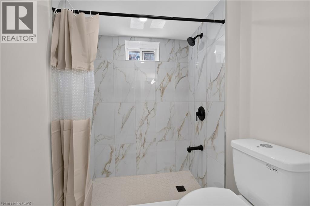 Walk-in shower with large format wall tiles, hexagonal floor tiles, and matte black fixtures - 331 East 17Th Street, Hamilton, ON