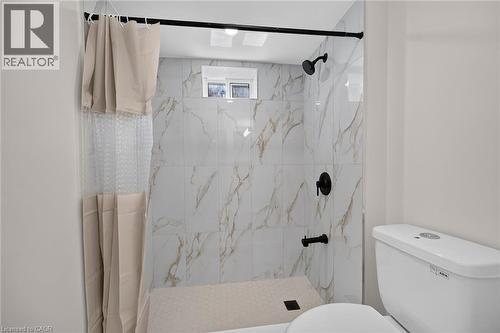 Walk-in shower with large format wall tiles, hexagonal floor tiles, and matte black fixtures - 331 East 17Th Street, Hamilton, ON 