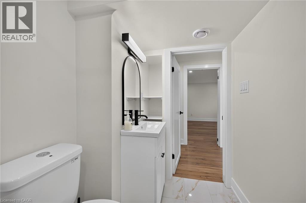 White vanity with an integrated sink, matte black faucet, and arched mirror - 331 East 17Th Street, Hamilton, ON
