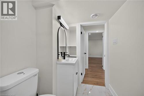 White vanity with an integrated sink, matte black faucet, and arched mirror - 331 East 17Th Street, Hamilton, ON 