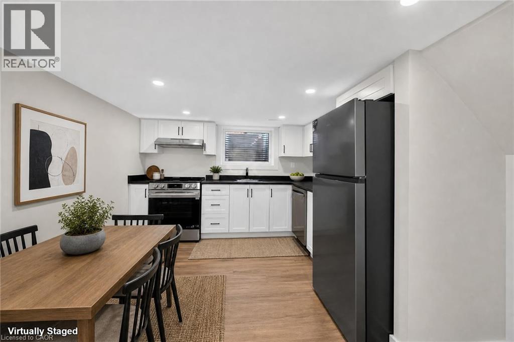 Modern kitchen with white cabinetry, dark countertops, stainless steel appliances, and wood-finish flooring - 331 East 17Th Street, Hamilton, ON