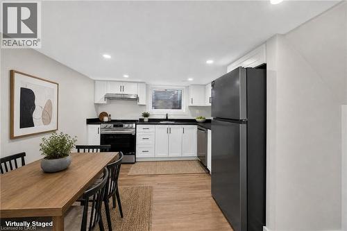 Modern kitchen with white cabinetry, dark countertops, stainless steel appliances, and wood-finish flooring - 331 East 17Th Street, Hamilton, ON 