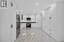 Gleaming tile flooring, extensive white cabinetry with matte black hardware, stainless steel appliances, recessed lighting, and dark countertops - 331 East 17Th Street, Hamilton, ON 