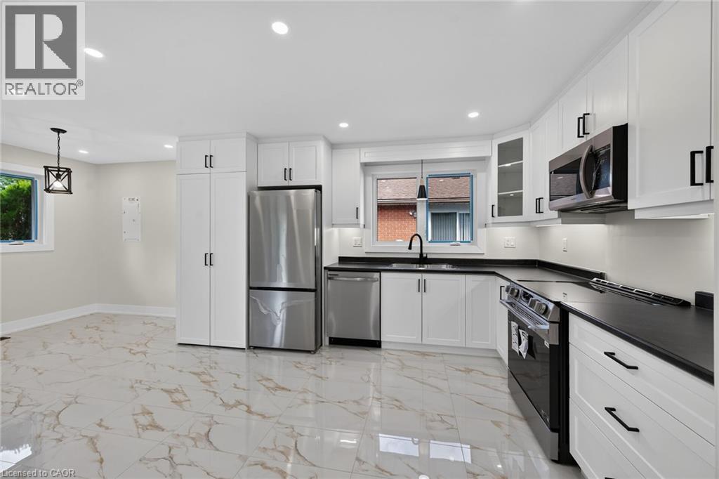 Contemporary kitchen featuring white cabinetry, dark countertops, and stainless steel appliances - 331 East 17Th Street, Hamilton, ON
