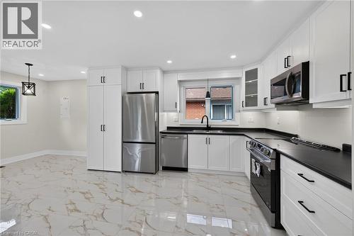 Contemporary kitchen featuring white cabinetry, dark countertops, and stainless steel appliances - 331 East 17Th Street, Hamilton, ON 