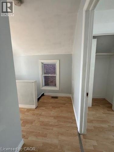 Wood-finish flooring throughout, bright window, and neutral wall tones - 1087 Cannon Street E, Hamilton, ON 
