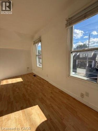 Wood-finish flooring with white walls, multiple windows, and a flush mount ceiling light - 1087 Cannon Street E, Hamilton, ON 