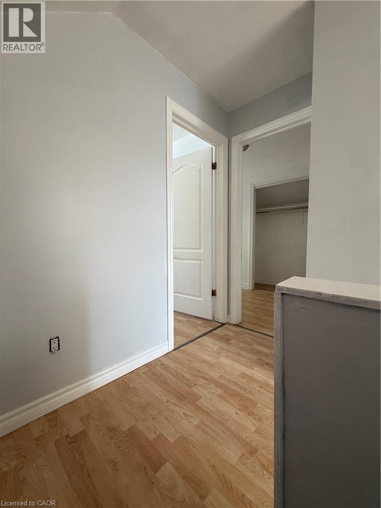 Wood-finish flooring throughout, white trim, light-colored walls, and solid core doors - 1087 Cannon Street E, Hamilton, ON