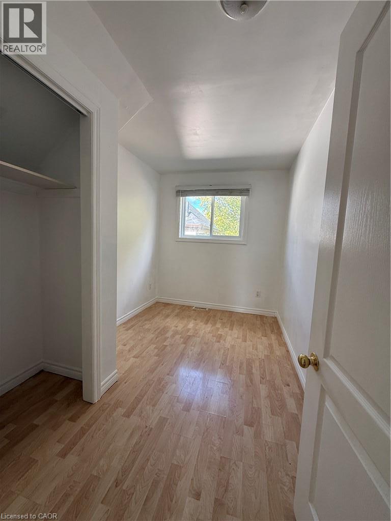 Wood-finish flooring, white walls, and a window with blinds - 1087 Cannon Street E, Hamilton, ON