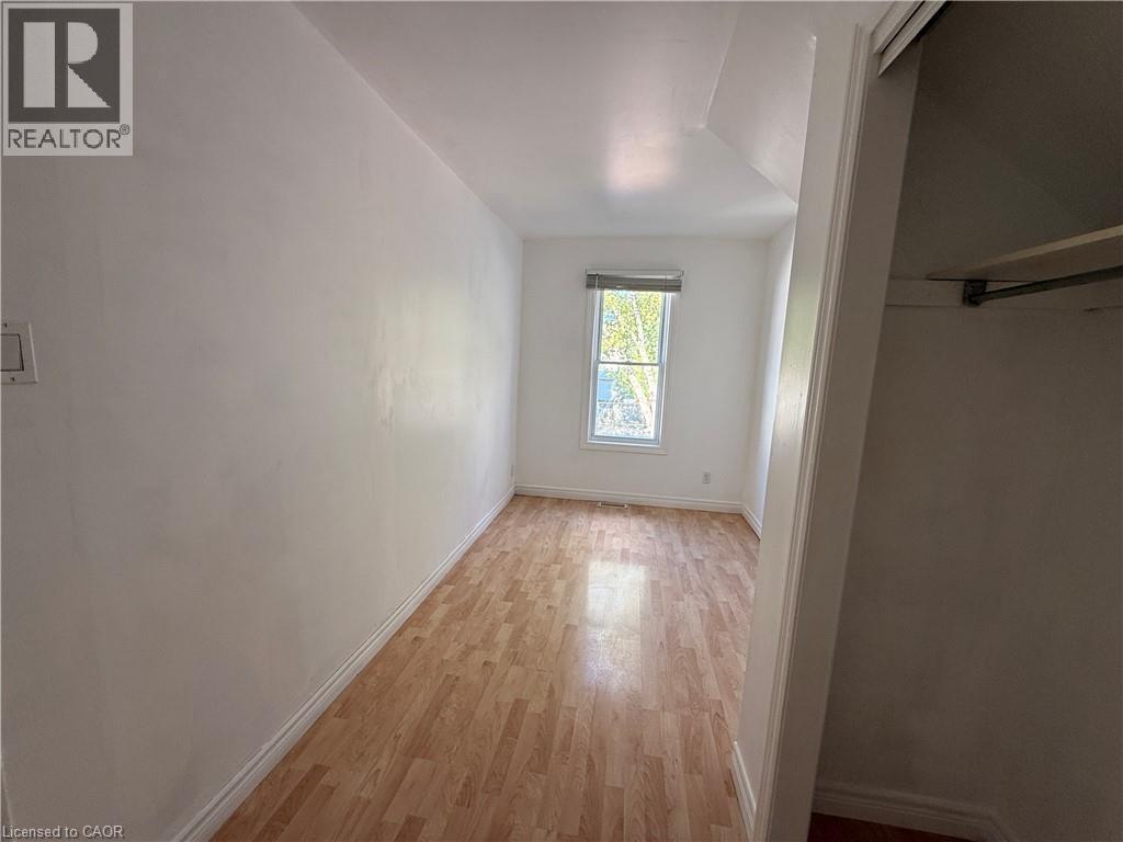 Wood-finish flooring, white painted walls, window with blinds, and an integrated closet with a hanging rod - 1087 Cannon Street E, Hamilton, ON