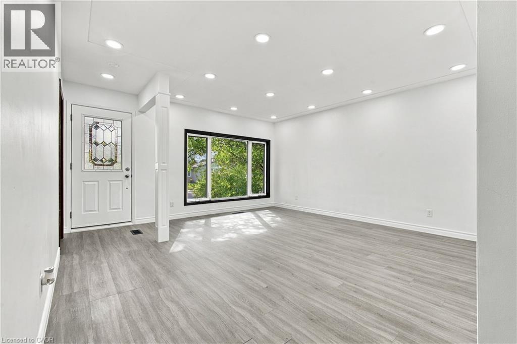 Bright interior space featuring wood-finish flooring, recessed lighting, and a front entry door with decorative glass inserts - 246 Hillcrest Road, Cambridge, ON