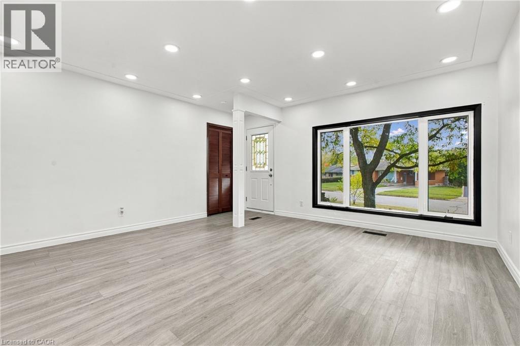 Recessed lighting, wood-finish flooring, white trim, and a large window with black framing - 246 Hillcrest Road, Cambridge, ON