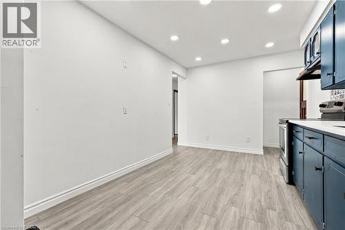 Recessed ceiling lighting, wood-finish flooring, white walls, dark blue cabinetry with black hardware, and stainless steel range - 246 Hillcrest Road, Cambridge, ON 