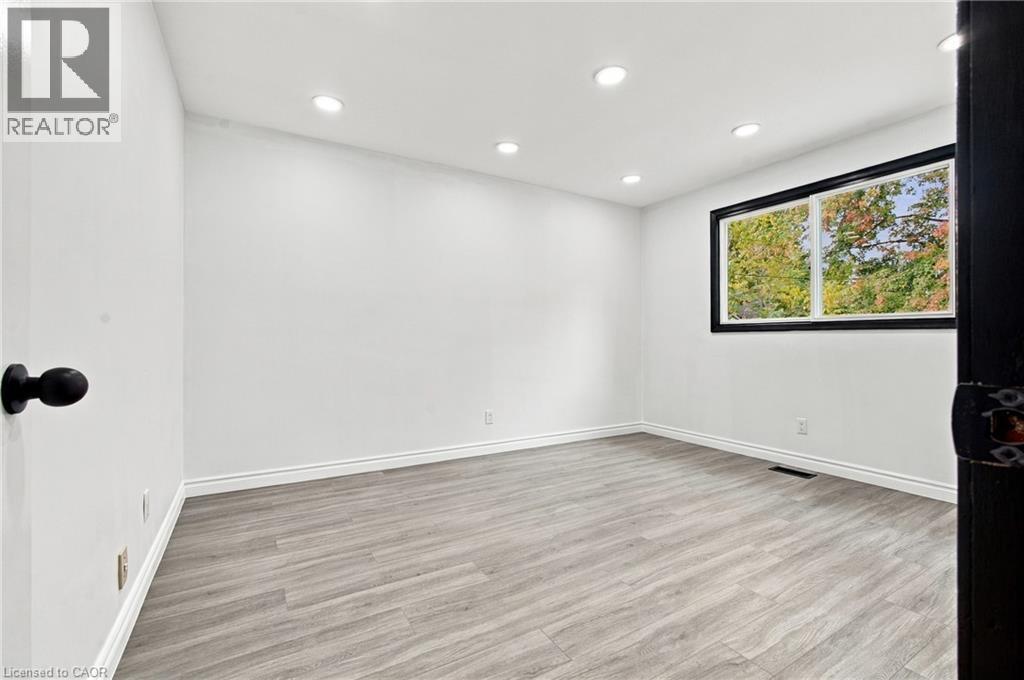 Recessed ceiling lighting, wood-finish flooring, white wall finishes, white baseboards, and a black-framed window - 246 Hillcrest Road, Cambridge, ON