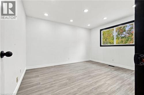 Recessed ceiling lighting, wood-finish flooring, white wall finishes, white baseboards, and a black-framed window - 246 Hillcrest Road, Cambridge, ON 