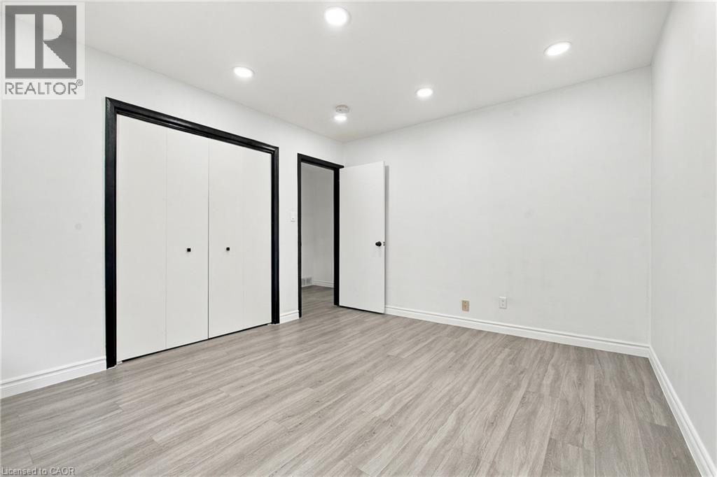 Recessed ceiling lighting, light wood-finish flooring, white walls, white bi-fold closet doors with black trim, and a white door with a black handle - 246 Hillcrest Road, Cambridge, ON