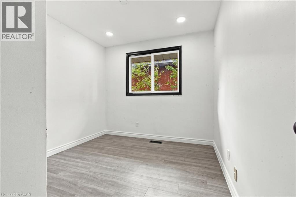 Recessed lighting, wood-finish flooring, white wall finishes, and a dark-framed window - 246 Hillcrest Road, Cambridge, ON