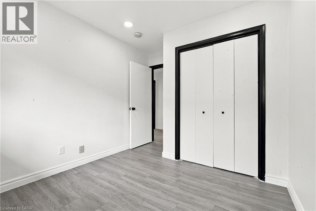 Wood-finish flooring, recessed lighting, white walls, and bi-fold closet doors with black trim - 246 Hillcrest Road, Cambridge, ON