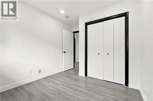 Wood-finish flooring, recessed lighting, white walls, and bi-fold closet doors with black trim - 246 Hillcrest Road, Cambridge, ON 