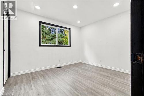 Recessed ceiling lights, wood-finish flooring, white walls, and a window with black trim - 246 Hillcrest Road, Cambridge, ON 
