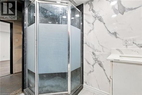 Corner shower enclosure with frosted glass panels, white marble-look wall tiling, and a white vanity with integrated sink - 246 Hillcrest Road, Cambridge, ON 