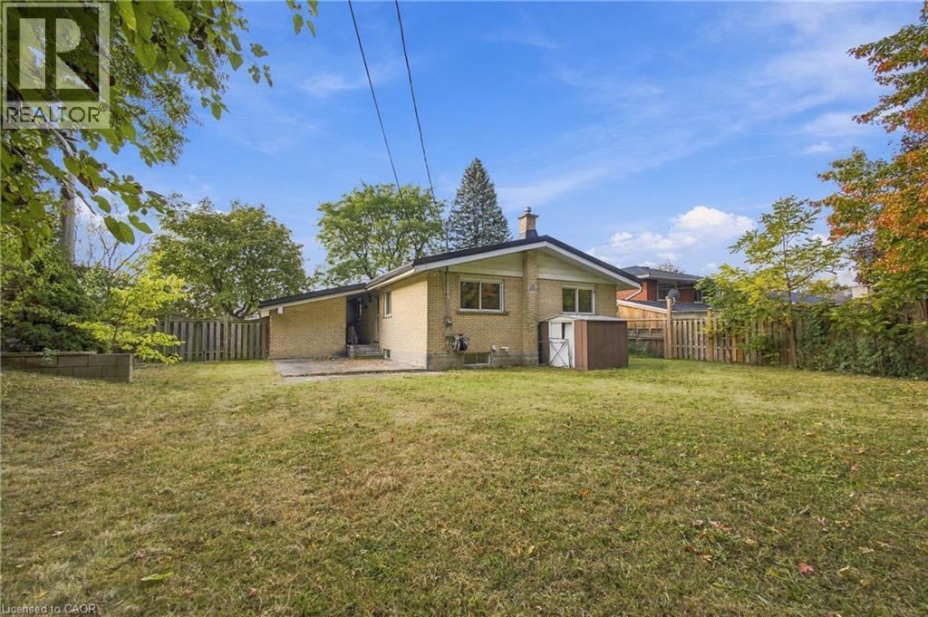 Expansive lawn area with a privacy fence, mature trees, and a concrete patio - 246 Hillcrest Road, Cambridge, ON