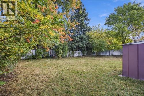 Expansive grassy yard with mature trees and a privacy fence, complemented by a purple utility shed - 246 Hillcrest Road, Cambridge, ON 