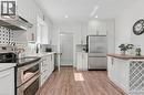 Kitchen featuring white cabinetry, stainless steel appliances, wood-finish flooring, a patterned tile backsplash, and a built-in wine rack - 164 Wilson Street, Hamilton, ON 