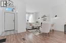 Bright open-concept living area featuring wood-finish flooring throughout, white shaker-style entry door with transom window, recessed ceiling lighting, and contemporary wall-mounted sconces - 164 Wilson Street, Hamilton, ON 