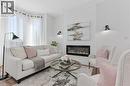 Contemporary fireplace with shiplap-accented surround, hardwood-style flooring, and a bay window - 164 Wilson Street, Hamilton, ON 