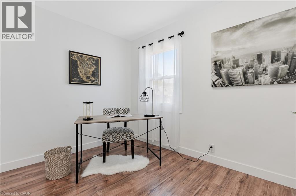 Dedicated workspace featuring a wood-finish desk with metal frame and cross-bracing, paired with upholstered seating - 164 Wilson Street, Hamilton, ON