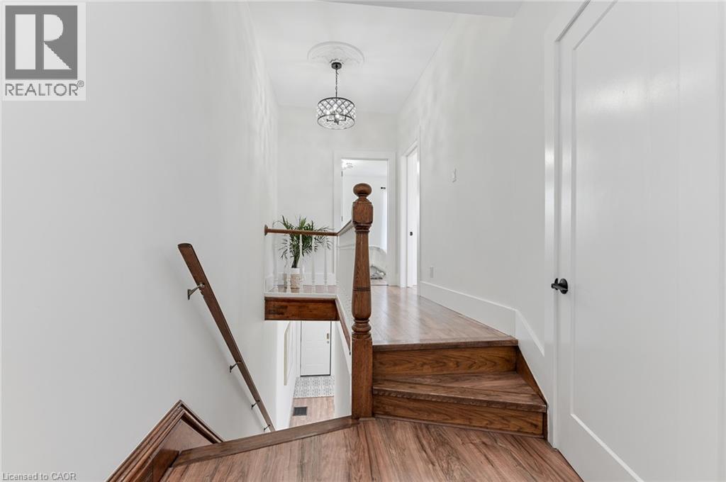 Wood-finish flooring throughout, solid wood staircase with balustrade, white interior doors, and a decorative ceiling medallion - 164 Wilson Street, Hamilton, ON