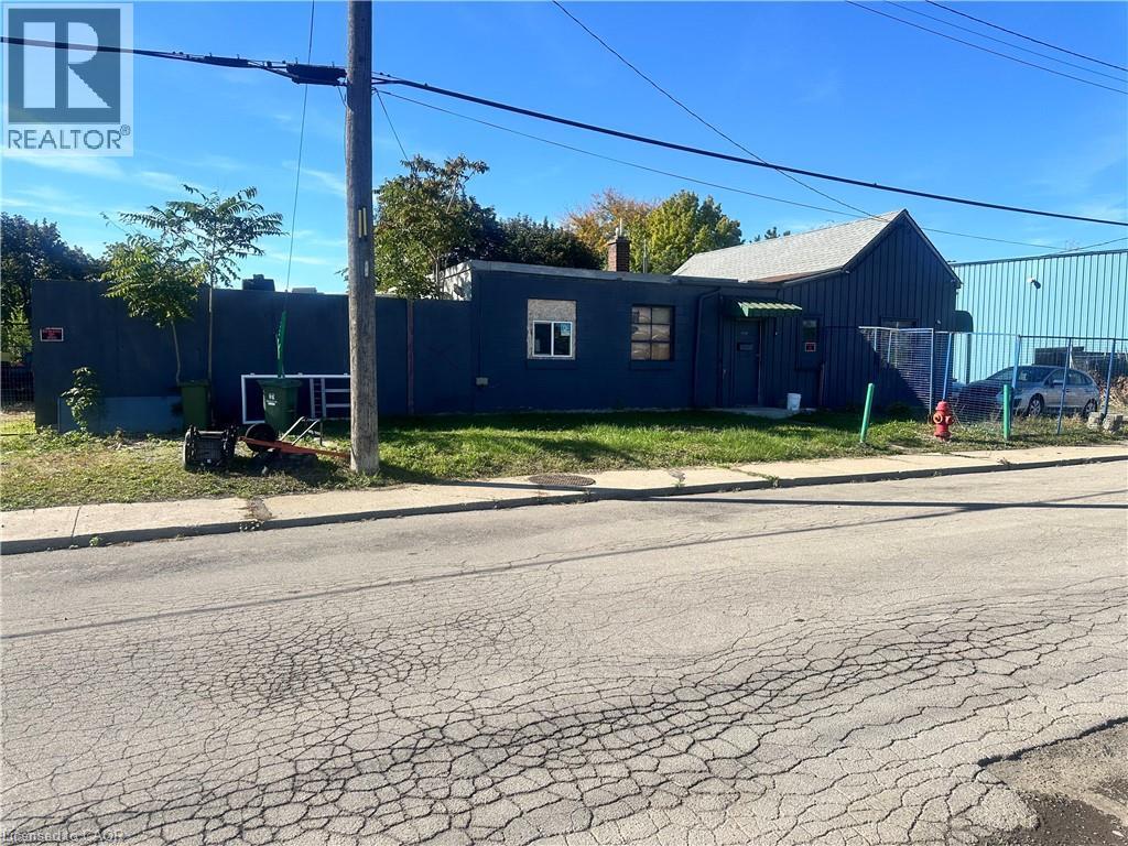Dark-toned exterior siding, rectangular window configurations, and perimeter fencing - 150 Princess Street, Hamilton, ON