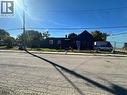Single-story exterior with dark-toned vertical siding, a pitched roofline, and an enclosed fenced perimeter - 150 Princess Street, Hamilton, ON 